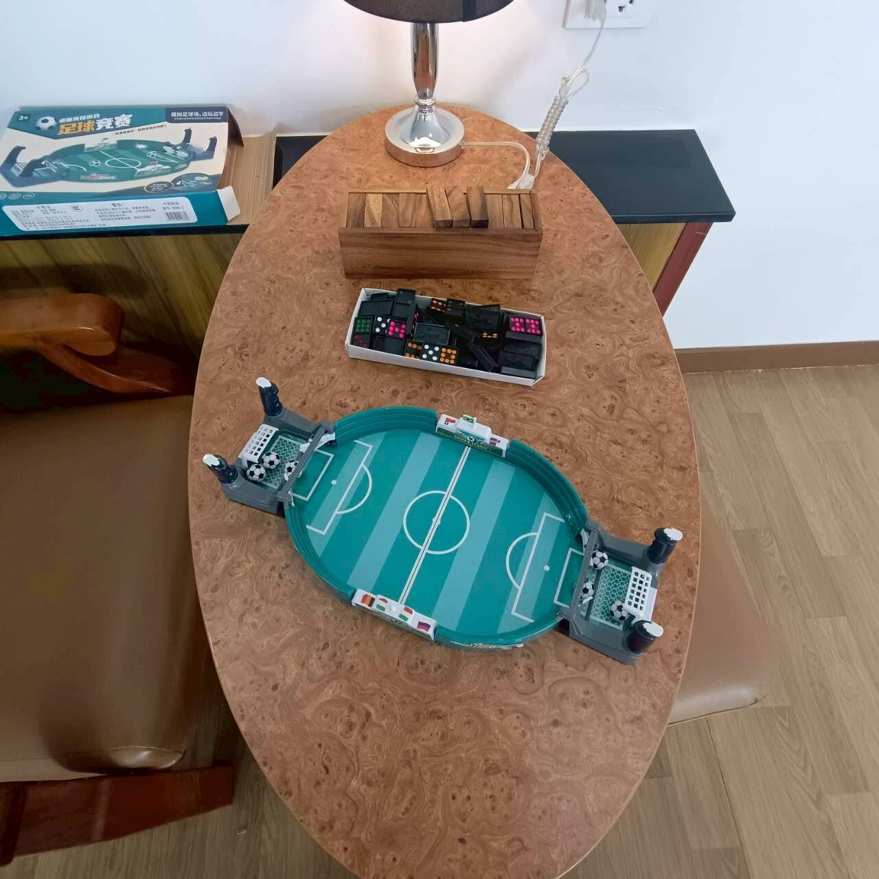 A table with a model soccer field, a remote control, and a box of batteries.