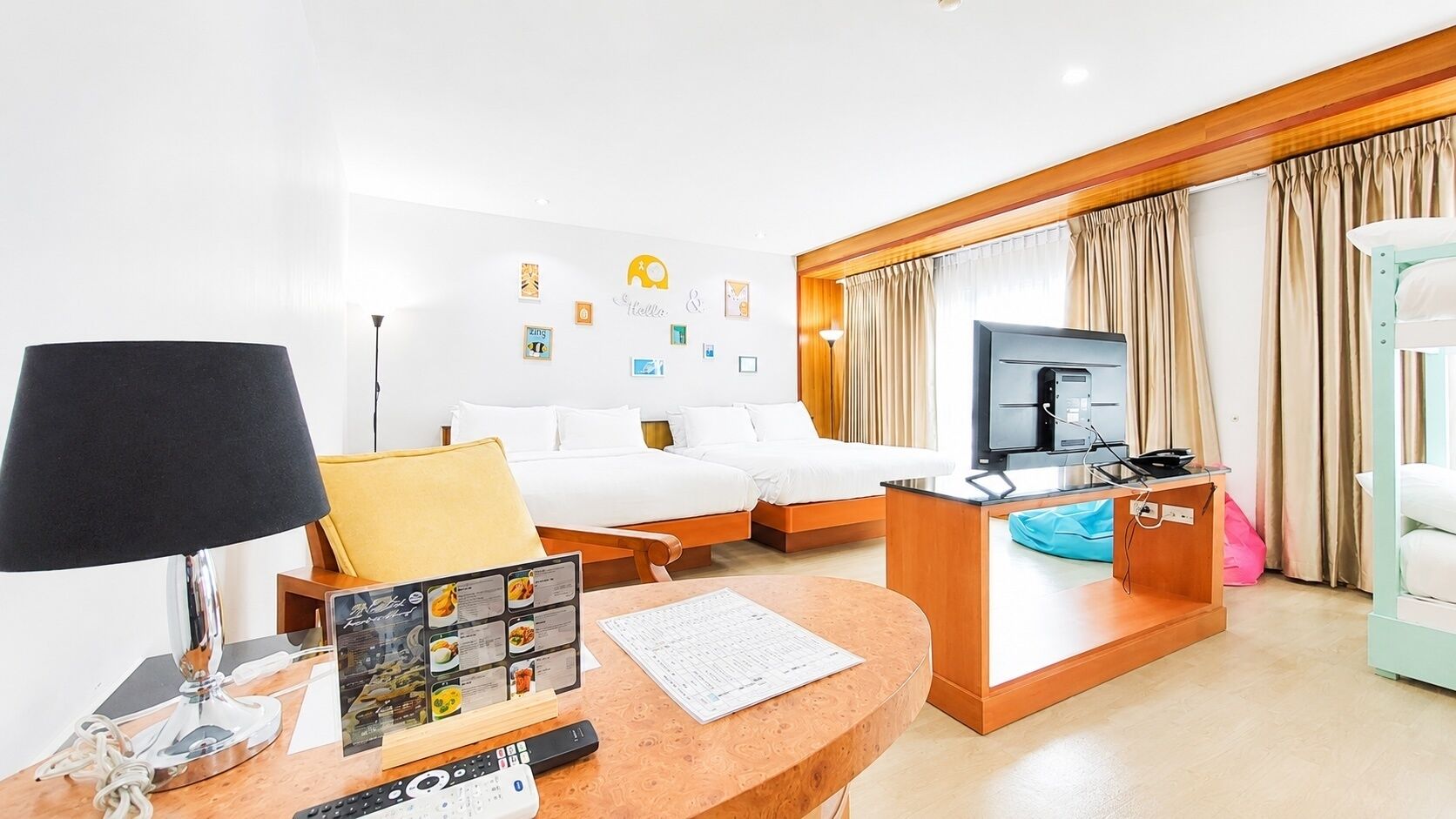Ein Hotelzimmer mit einem Bett, einem Schreibtisch mit Lampe, einem Fernseher und einem Fenster mit Vorhängen.
