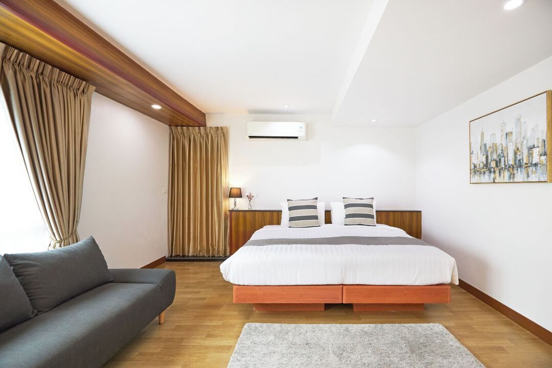 Une chambre moderne avec un grand lit, un canapé et un appareil de climatisation.