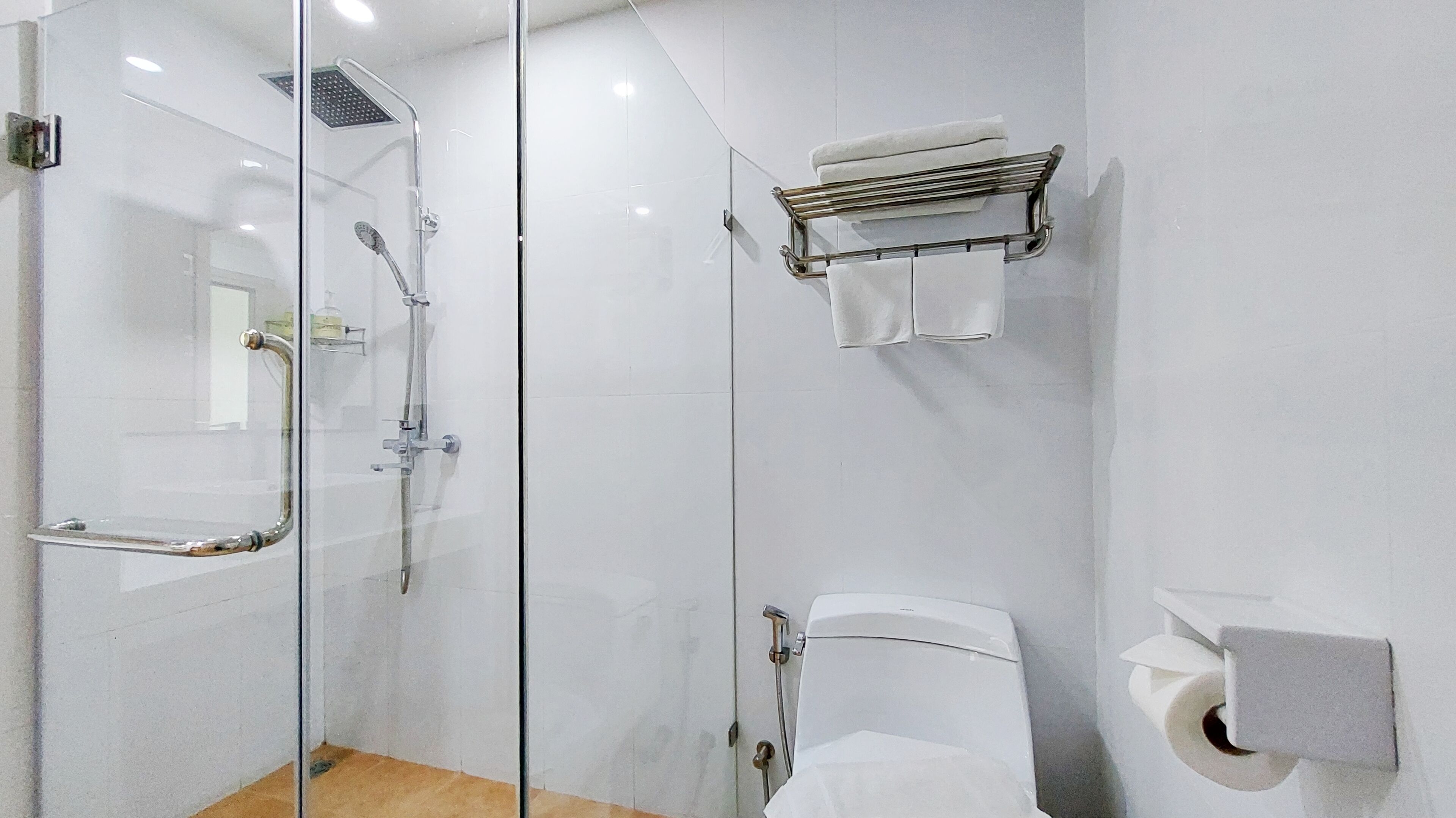 Un baño moderno con cabina de ducha de vidrio, inodoro y perchero para toallas.