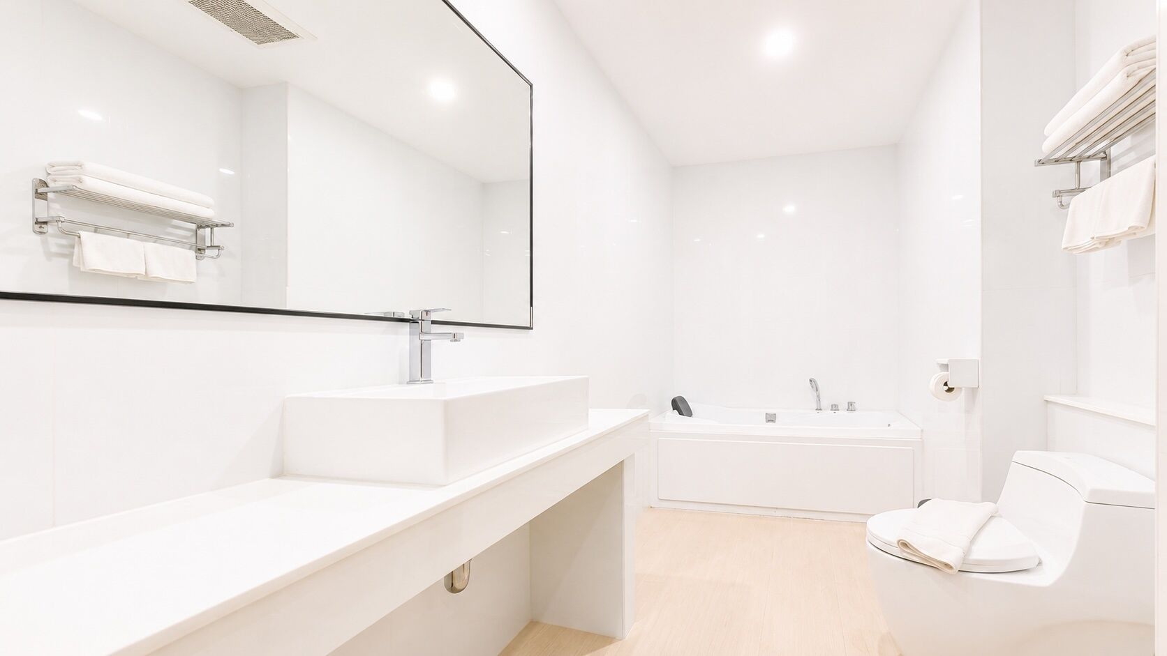 A modern bathroom with a white sink, mirror, and bathtub.