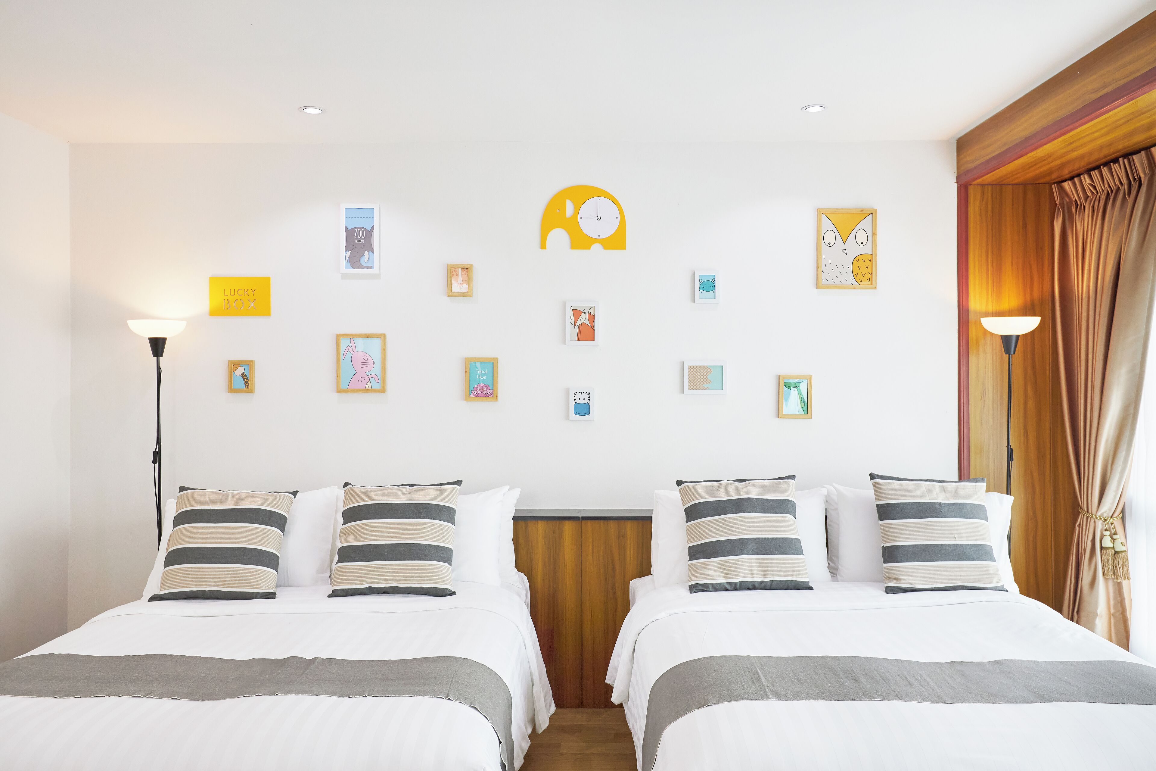 A hotel room with two beds, a wooden headboard, and a variety of wall art.