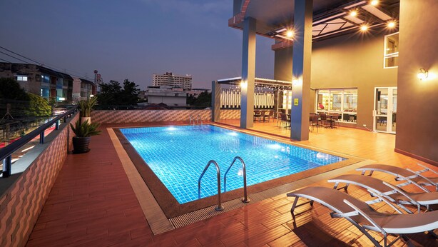 A rooftop pool area with a clear blue pool, lounge chairs, and a bar area with seating. - Cozy Don Mueang Hotel (Bangkok)