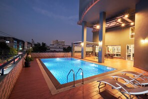 A rooftop pool area with a clear blue pool, lounge chairs, and a bar area with seating. - Cozy Don Mueang Hotel (Bangkok)
