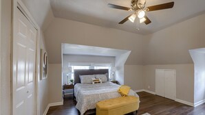 Une chambre à coucher avec un lit, un banc, un ventilateur de plafond et une fenêtre.