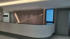 A modern reception desk with a curved design, a vertical slatted panel, and a flat-screen monitor. - Homeinn · neo (Beijing Ping'anli Subway Station) (Beijing)