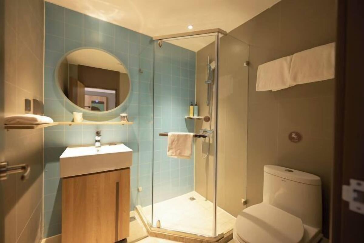 A modern bathroom with a glass-enclosed shower, a wooden vanity, and a toilet.