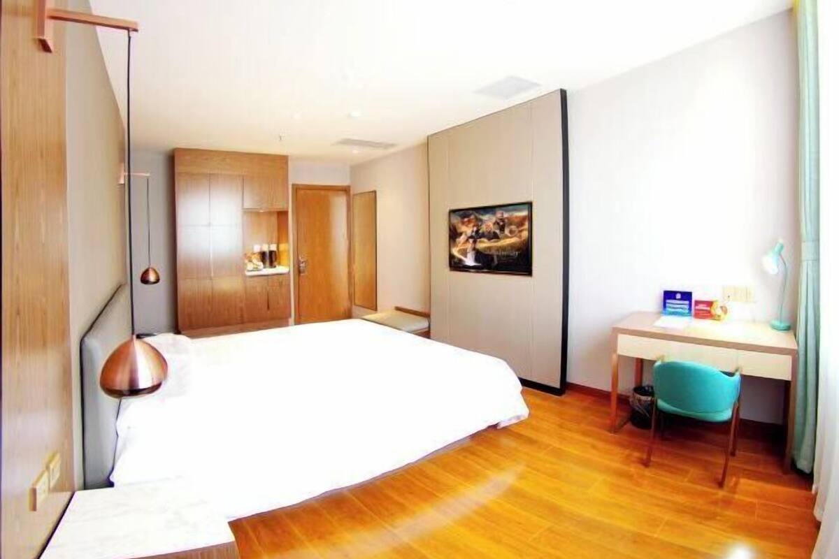 A hotel room with a bed, a desk, a chair, and a wardrobe.