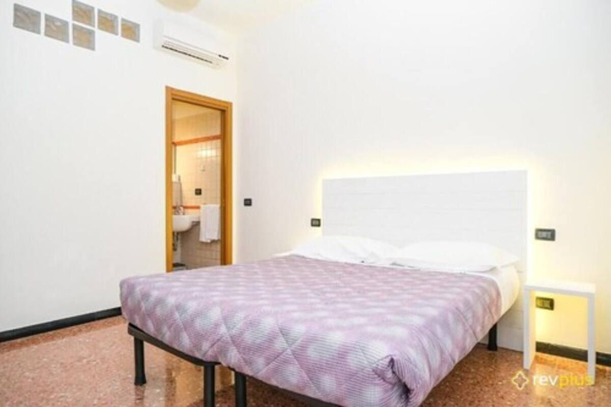 Une chambre à coucher comprenant un lit, une table de chevet et un climatiseur fixé au mur.
