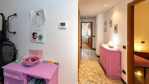 A hallway with a pink cabinet, a bulletin board with notices, and a thermostat.