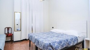 A bedroom with a bed, a chair, a mirror, and a window with curtains.