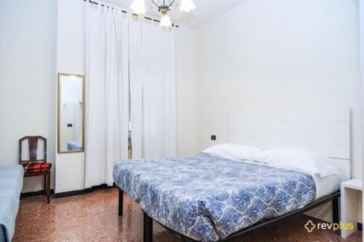 Une chambre à coucher avec un lit, une chaise, un miroir et une fenêtre avec des rideaux.