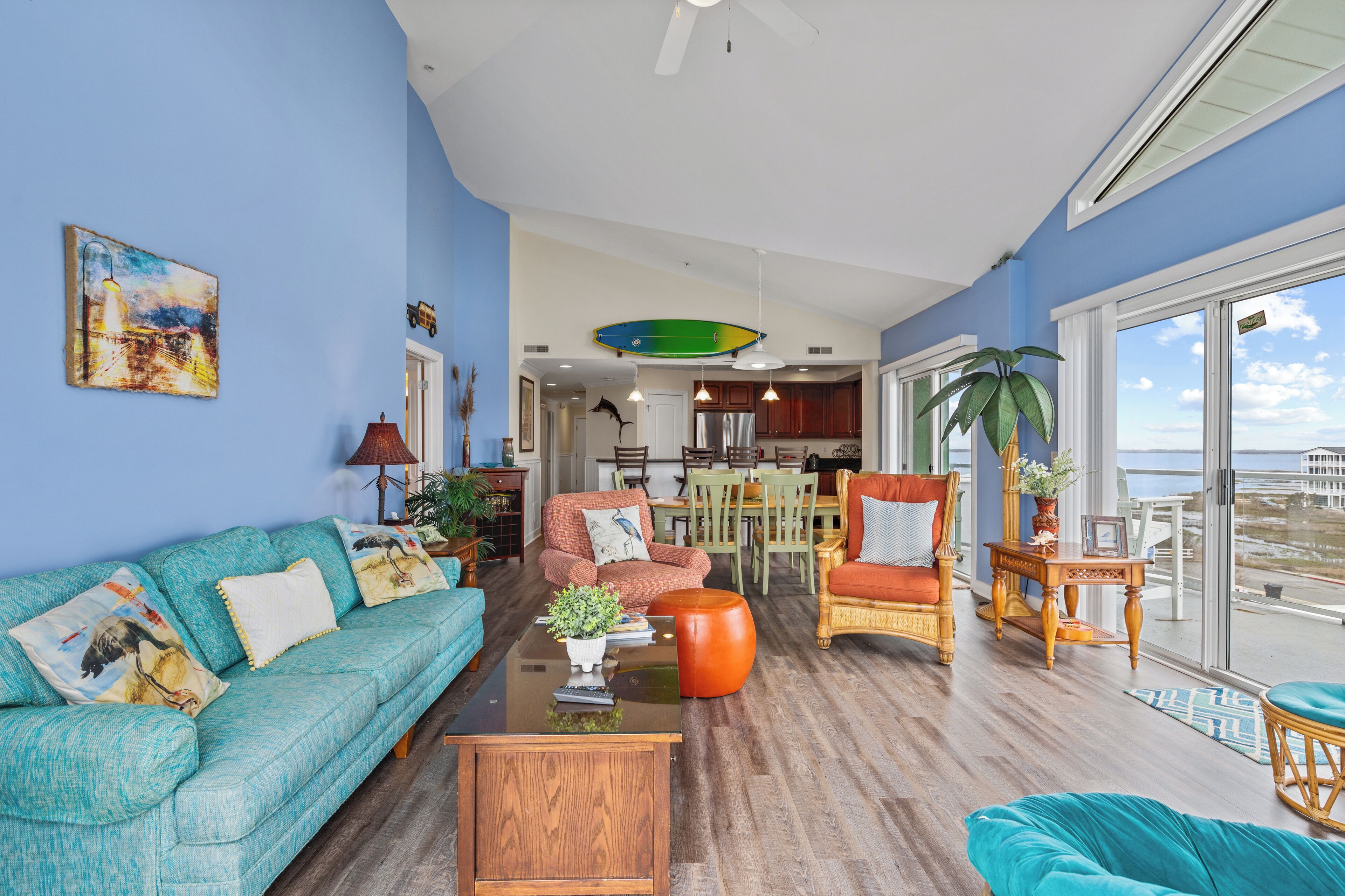 A spacious living room with a large window, a dining area, and a kitchen.