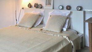 Un dormitorio con cama, lámparas de noche, un reloj y un cuadro en la pared.