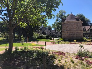 A historic building with a round tower, surrounded by a well-maintained garden with various plants and a paved walkway. - Château de Saint-Clair (Bordeaux-Saint-Clair)