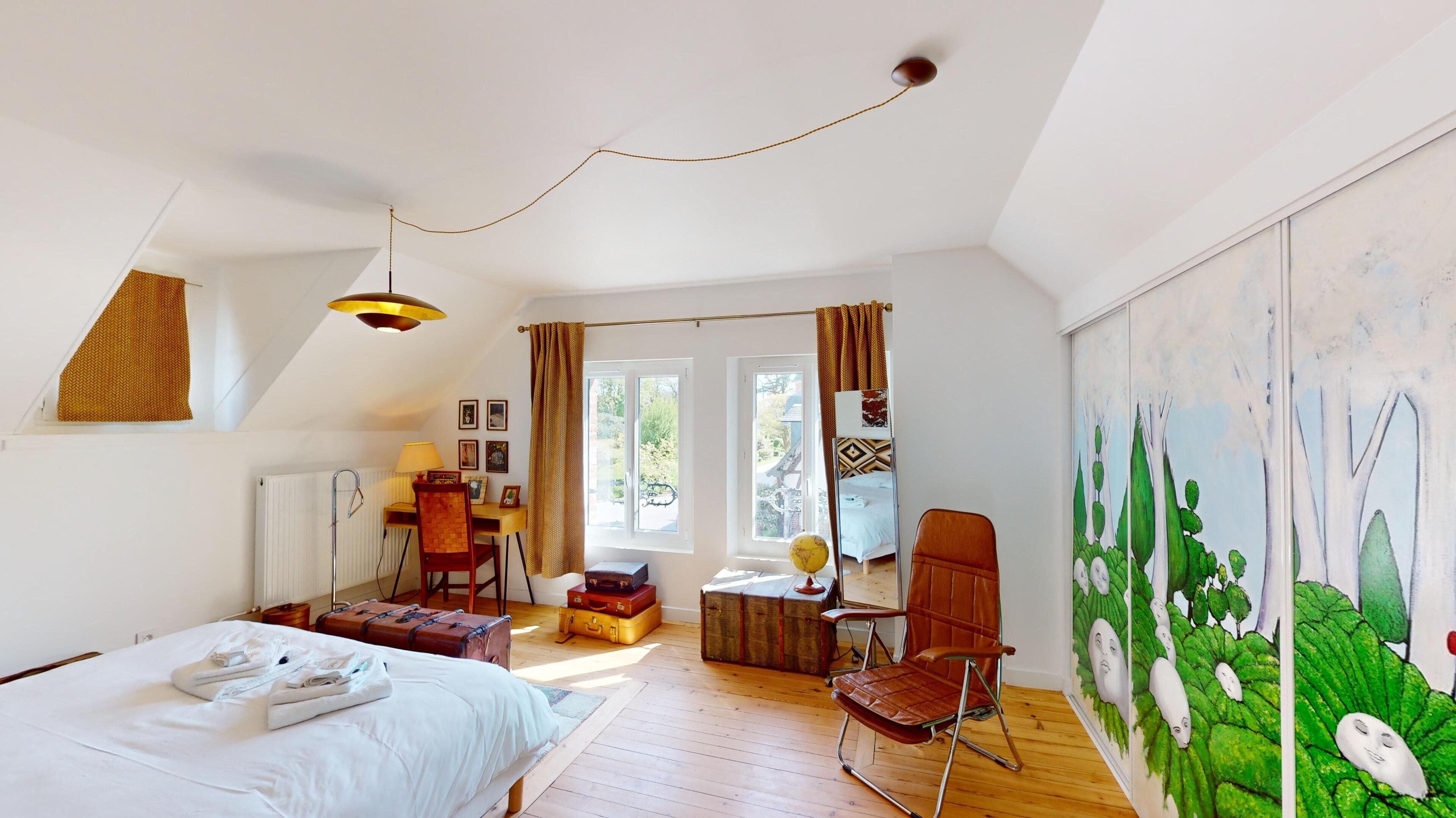A bedroom with a bed, a desk, a chair, a globe, and a painting of ghostly figures.