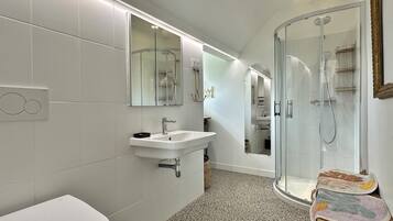 A modern bathroom with a white sink, mirror, and shower.
