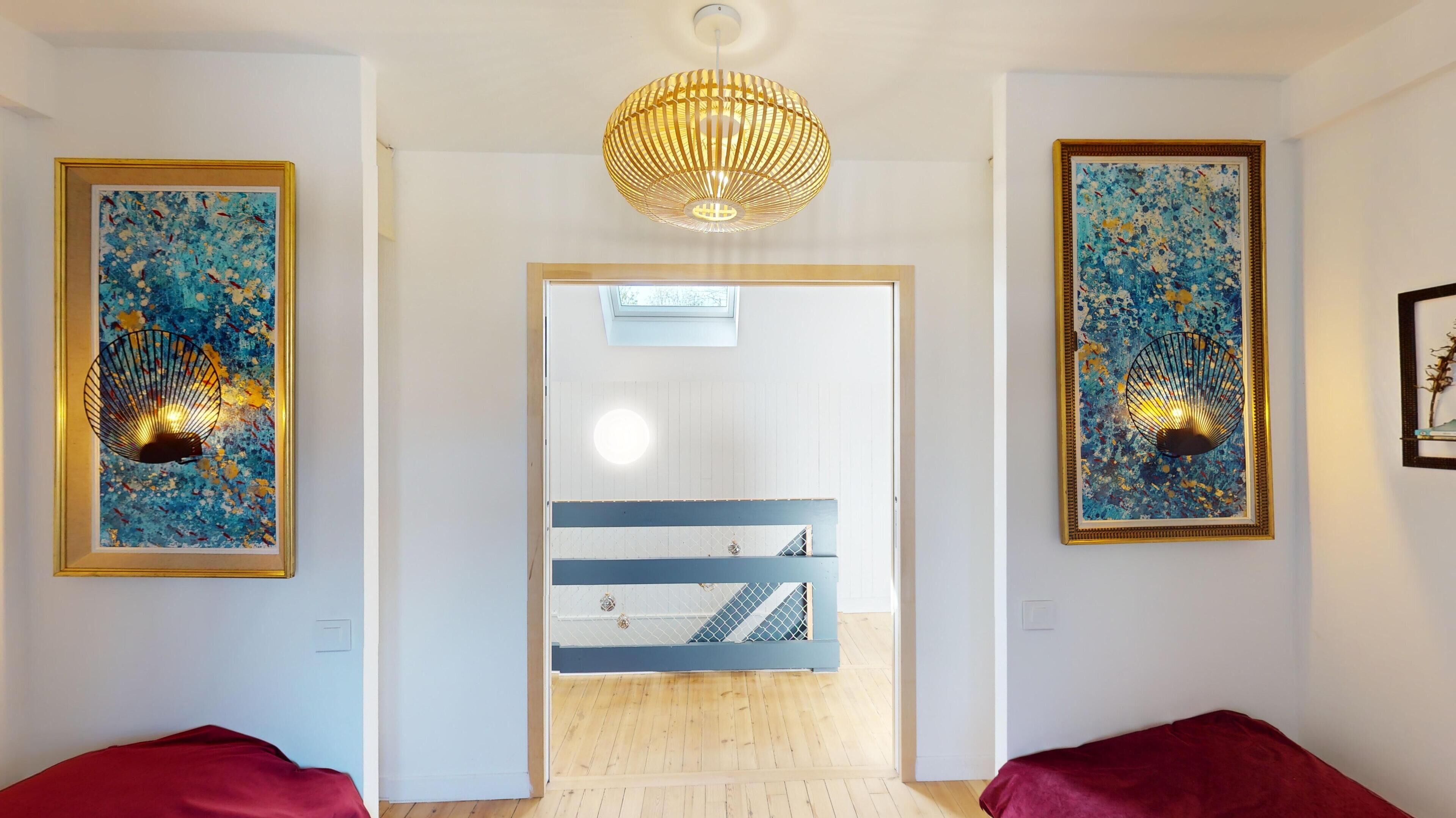 A hallway with two red upholstered chairs, a wooden floor, and a ceiling light fixture.