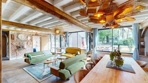 Amplia sala de estar con techos altos, vigas de madera a la vista y un gran ventanal con vistas al exterior.