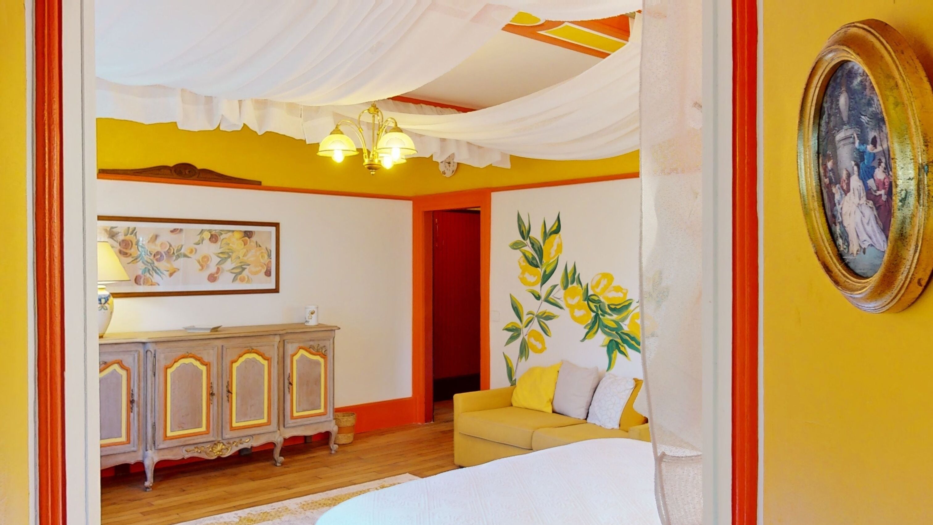 A bedroom with a bed, a yellow sofa, a cabinet, and a painting on the wall.