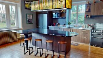 Una cocina moderna con una isla grande, taburetes de bar, electrodomésticos de acero inoxidable y armarios de madera.