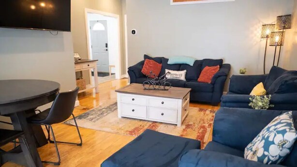Un salon moderne avec un canapé bleu foncé, une table basse blanche et une table à manger avec des chaises.