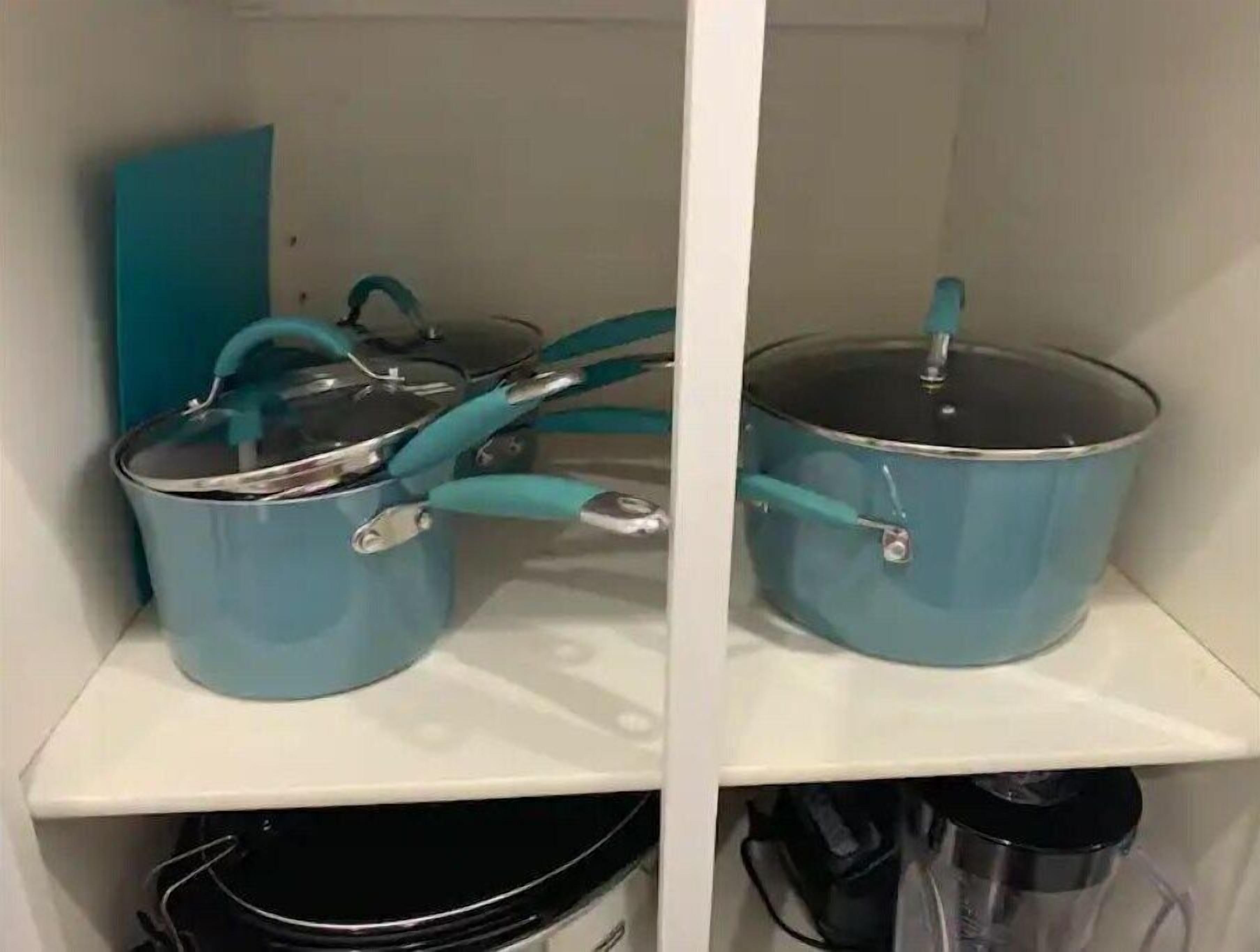 Una cocina con dos ollas azules sobre estantes blancos.