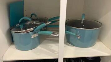 Una cocina con dos ollas azules sobre estantes blancos.