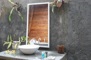 Un baño con un espejo grande, un lavamanos blanco y una puerta de madera.