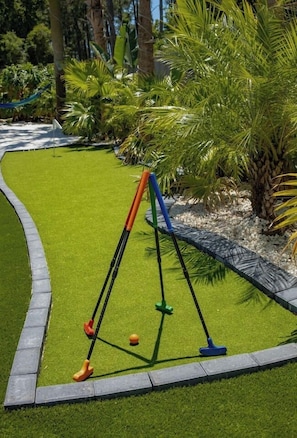 A well-maintained lawn with a croquet set and a small ball.