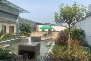 A courtyard with a fountain, seating area, and greenery. - Shanggao Hotel (Chongqing)