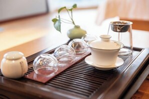 A tray with a teapot, cups, and a small vase on a wooden table. - Shanggao Hotel (Chongqing)
