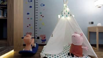 Un espace de jeux pour enfants avec une tente, un tableau pour mesurer la taille et une peluche de Peppa Pig.