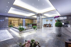 A modern hotel lobby with a reception desk, seating area, and decorative plants. - Shanggao Hotel (Chongqing)