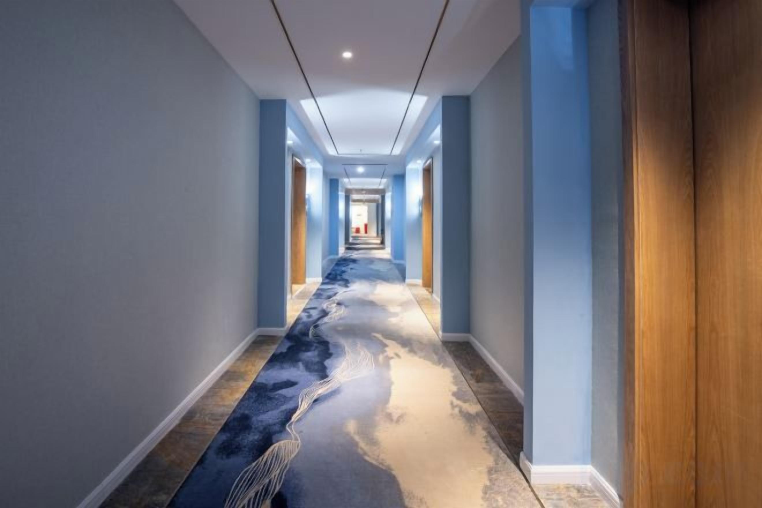 A hallway with a long carpet featuring a blue and white abstract design.