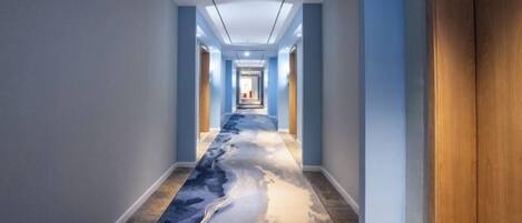 A hallway with a long carpet featuring a blue and white abstract design.