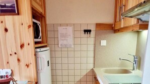 A compact kitchen with wooden cabinets, a microwave, a dishwasher, and a sink. - 100m from ski slopes, Ground floor, view valley, balcony, tv, 46m², Montalbert (La Plagne)