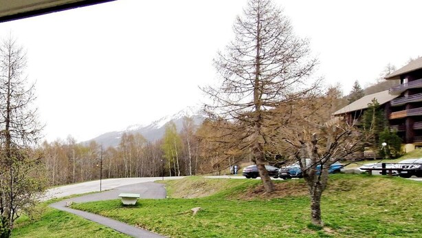 A view of a mountain landscape with a road curving through a grassy area, surrounded by trees and a building with balconies. - 100m from ski slopes, Ground floor, view valley, balcony, tv, 46m², Montalbert (La Plagne)