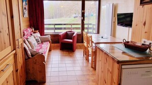 A cozy room with a wooden bench, a red chair, a small table, and a kitchen area with a dishwasher. - 100m from ski slopes, Ground floor, view valley, balcony, tv, 46m², Montalbert (La Plagne)