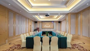 A conference room with a long table, white chairs, and a projector screen. - Vienna International Hotel Foshan Qiandenghu Guicheng Subway Station Branch (Foshan)