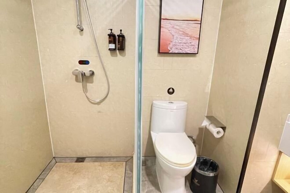 Un baño con ducha, inodoro y un cubo de basura.