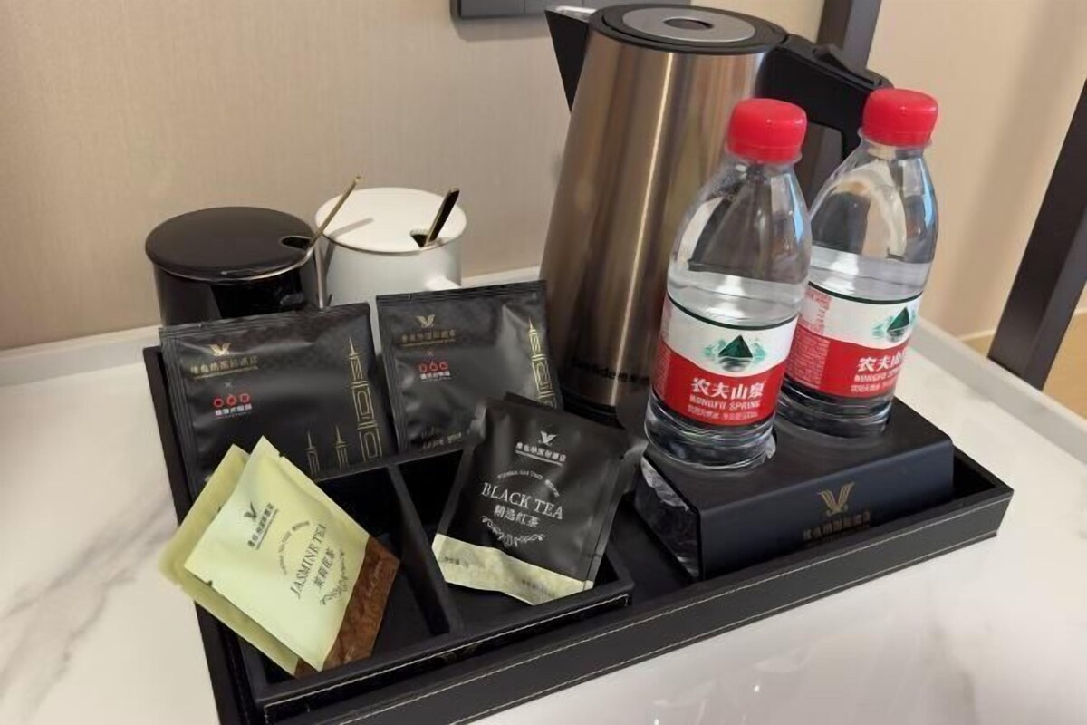 Una bandeja con bolsitas de té, agua embotellada y una termo.