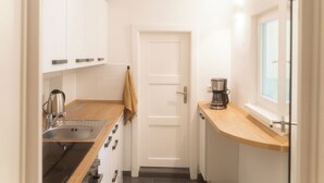 Una cocina compacta con armarios blancos, cafetera y ventana.