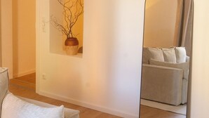 Una sala de estar moderna con un sofá, un espejo y una obra de arte colgada en la pared.