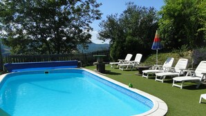 A rectangular swimming pool with a blue interior, surrounded by artificial grass and white lounge chairs. - Bienvenue Dans les Alpes de Hautes Provence . A Proximité des Gorges du Verdon (Beynes)