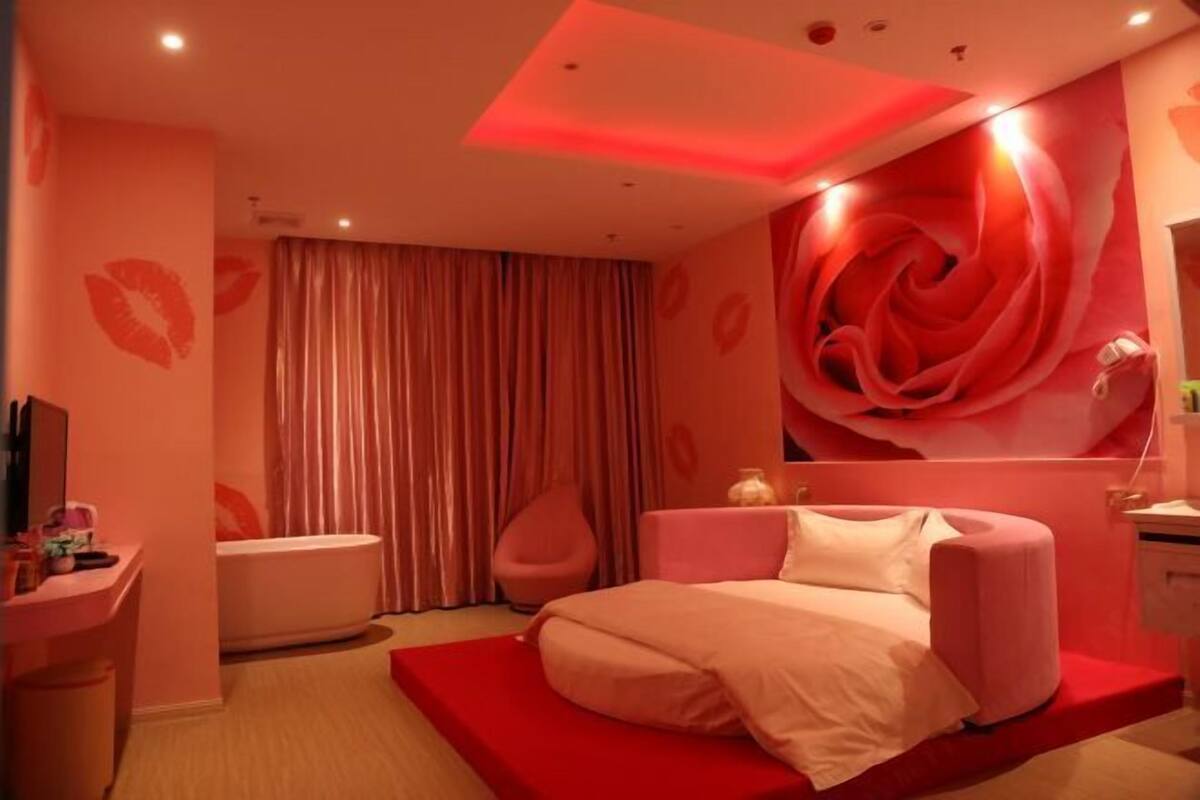 A bedroom with a bed, a vanity, a chair, and a large wall decoration.