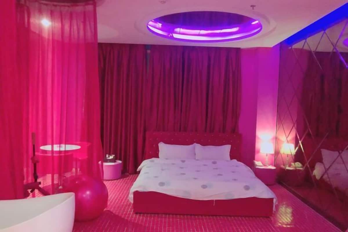 A bedroom with a bed, curtains, a round ceiling light, and a wall-mounted lamp.