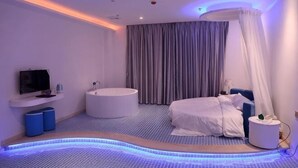 Un dormitorio moderno con cama, bañera, televisor y butaca de masaje instalada en el techo.