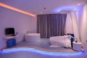 A modern bedroom with a bed, a bathtub, a TV, and a ceiling-mounted massage chair. - Love Me Couples' Theme Hotel (Guangzhou)