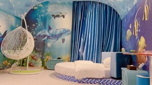 Una habitación con una cama, una silla colgante y un mural con escenas submarinas.